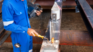 Non-destructive testing technician applying penetrant on metal joint